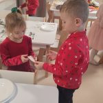 Dzieci w strojach świątecznych dzielą się opłatkiem i składają sobie życzenia.