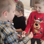 Dzieci w strojach świątecznych dzielą się opłatkiem i składają sobie życzenia.