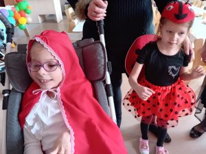Cztery uśiechnięte dziewczynki, ubrane w sukienki stoją i pozują do zdjęcia.ją do zdjęcia