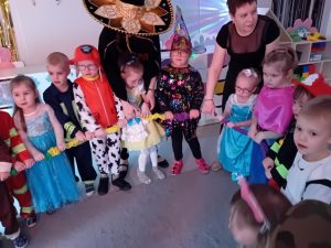 Grupa uśmiechniętych dzieci razem tańczą w kole.