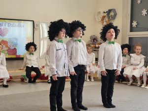 Trzech chłopców w czarnych perukach recytuje wiersz.