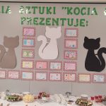 Szara ściana na niej koty i portrety babci i dziadka.