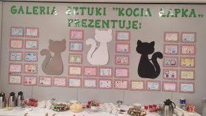 Szara ściana na niej koty i portrety babci i dziadka.