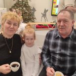 Dziewczynka pozuje do zdjęcia razem z babcią i dziadkiem.