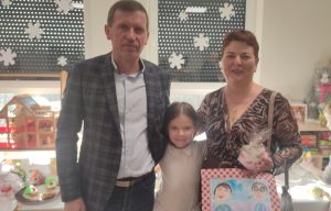 Dziewczynka pozuje do zdjęcia razem z babcią i dziadkiem.