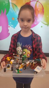 Dziewczynka pokazuje swoje konstrukcje z klocków LEGO.