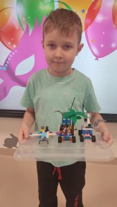Chłopiec pokazuje swoje konstrukcje z klocków LEGO.