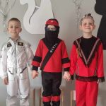 Trzech chłopców pozuje w strojach karnawałowych do zdjęcia.