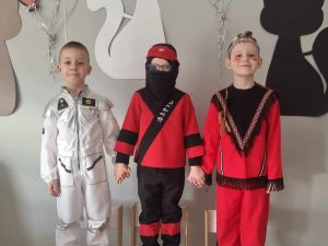 Trzech chłopców pozuje w strojach karnawałowych do zdjęcia.