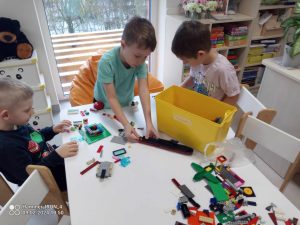 Dzieci przy stoliku tworzą budowle z klocków LEGO.