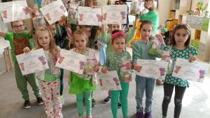 Dzieci nagrodzone pozują do wspólnego zdjęcia z dyplomami i nagrodami.
