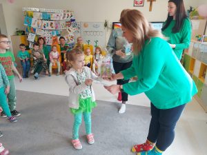 Pani dyrektor Izabela ubrana w zielony sweter i kolorowe skarpetki wręcza dziewczynce dyplom i nagrodę.