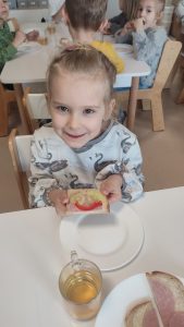 Dziewczynka trzyma w ręce kolorową kanapkę z produktów ekologicznych.