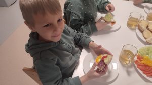 Chłopiec trzyma w ręce kolorową kanapkę z produktów ekologicznych.