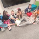 Dzieci nóżkami podają sobie zimny balonik. Są również dzieci niepełnosprawne.