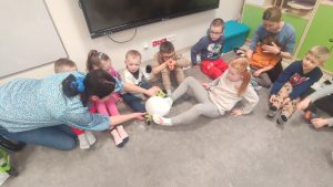 Dzieci nóżkami podają sobie zimny balonik. Są również dzieci niepełnosprawne.