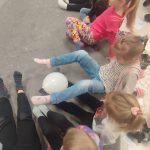 Dzieci nóżkami podają sobie zimny balonik. Są również dzieci niepełnosprawne.