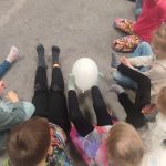 Dzieci nóżkami podają sobie zimny balonik. Są również dzieci niepełnosprawne.