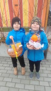 Dwoje dzieci prezentują znalezione koszyczki z prezentami.