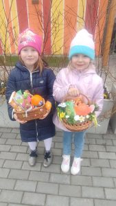 Dwoje dzieci prezentują znalezione koszyczki z prezentami.