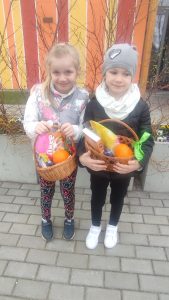 Dwoje dzieci prezentują znalezione koszyczki z prezentami.