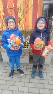 Dwoje dzieci prezentują znalezione koszyczki z prezentami.