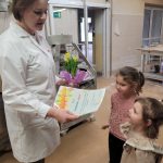 Dwie dziewczynki częstują się ciasteczkami podawanymi przez pracownicę piekarni