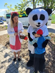 Chłopiec przytula maskotkę - Pandę stojącą obok Pani Jarzębinki