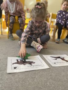 Dziewczynka odszukuje i dopasowuje dinozaura do odpowiedniego obrazka.