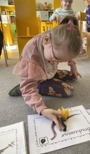 Dziewczynka odszukuje i dopasowuje dinozaura do odpowiedniego obrazka.