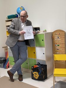 Pan Agent ubezpieczeniowy, stoi podparty o szafkę i prezentuje swój zawód.