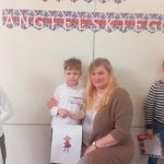 Chłopiec w białej koszuli pozuje do zdjęcia razem z nauczycielką.