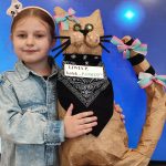 Dziecko pozuje ze swoim kotem wykonanym z różnorodnych odpadów - recyklingu.