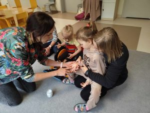 Terapeuta smaruje dziewczynce rączkę olejem kokosowym.
