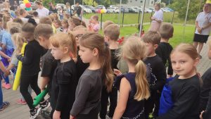 Dzieci ubrane na czarno oczekują na swój występ na festynie.