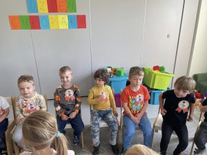 Chłopcy siedzą na krzesłach z orderami z okazji dnia chłopaka