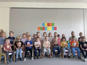 Wspólne zdjęcie dziewczynek i chłopców z upominkami z okazji Dnia Chłopaka