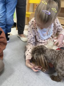 Dziewczynka karmi pieska trzymając karmę na dłoni.