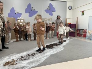Dzieci przechodzą po ścieżce sensorycznej.
