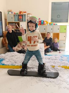 Chłopiec stoi na desce snowboardowej.
