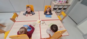 Dzieci siedzą przy stoliku i próbują wcześniej przygotowany koktajl bananowy.