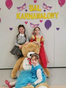 Trzy dziewczynki pozują do zdjęcia z misiem