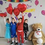 Czworo dzieci pozuje do zdjęcia unosząc do góry balony