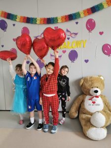 Czworo dzieci pozuje do zdjęcia unosząc do góry balony