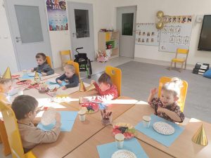 Dzieci świętują urodziny Tymona. Siedzą przy stolikach i częstują się przygotowanymi przekąskami.