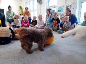 Dzieci w kole, piesek pośrodku bawi się piłką