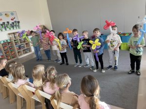 Chłopcy stoją i trzymają kwiaty zrobione z balonów.