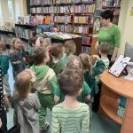 Dzieci słuchają pani bibliotekarki i poznają zasady korzystania z biblioteki.