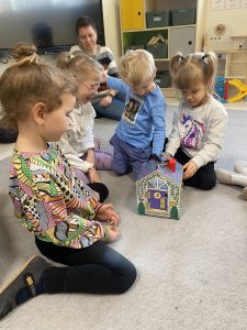 Dzieci i Pani bawią się drewnianym domkiem