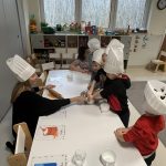 Dzieci zagniatają swoimi rączkami ciasto na pizzę.